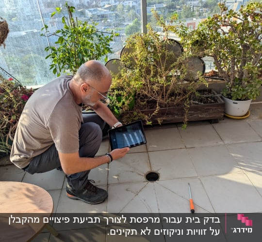 אדם בודק רצפה עם טאבלט וכלי עבודה